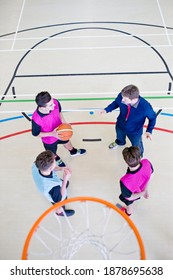 High-angle Vertical Shot Of A Gym Teacher Guiding High School Students With A Basketball During A Gym Class.