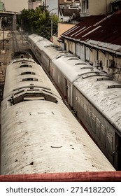 High-angle vertical view capturing the long, cylindrical roof of a stationary train on the tracks. Highlights industrial transportation, rail infrastructure, and travel. Evokes a sense of vintage urba
