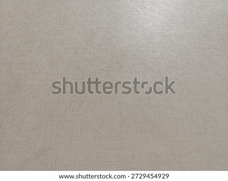 High-angle view of beige fabric texture background with subtle linen pattern and soft lighting