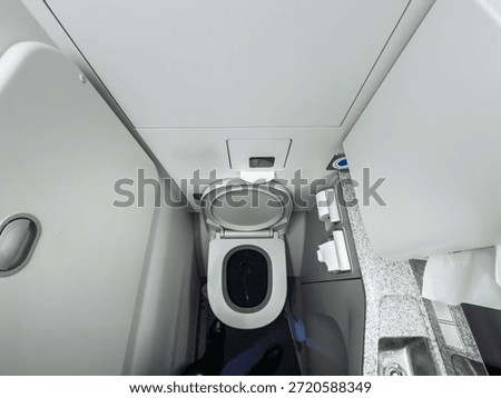 High-angle view of a compact lavatory inside a commercial airplane during a flight, some airplaine toilets. The small restroom features a toilet bowl, sink, and standard amenities for passengers.