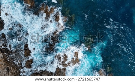 High-angle view of crystal clear turquoise water washing over submerged reefs and rocky outcrops at the base of Cape Patton.