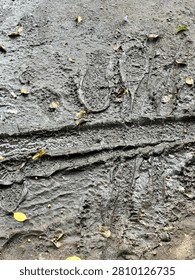 High-angle view of deep wet mud with detailed footprints and a bicycle tire track texture after heavy rain.