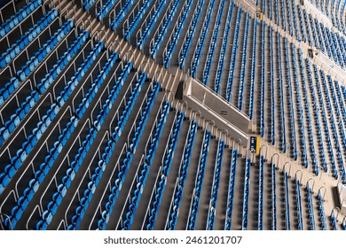High-angle view of empty blue and gray stadium seats arranged in a repetitive pattern, capturing the quiet before an event. - Powered by Shutterstock