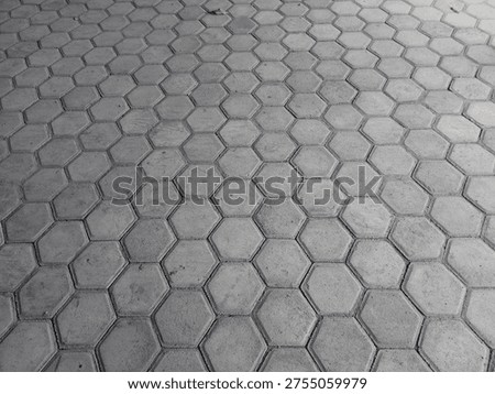 High-angle view of gray hexagonal concrete paving blocks pattern, creating a seamless geometric texture for outdoor flooring and urban architecture.