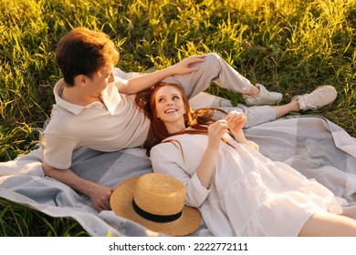 High-angle view of happy smiling young couple in love lying together looking at each other on sunny day, enjoying each other. Loving boyfriend and girlfriend lying on blanket in sunlit field. - Powered by Shutterstock