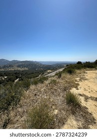 A high-angle view looking down at the steep twisting mountain grade road layout wrapping along the forested side of Palomar Mountain, California.