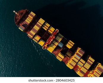 A highangle view of a massive cargo vessel loaded with multicolored shipping containers navigating deep waters near si racha chon buri thailand.