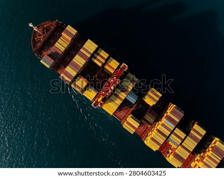 A highangle view of a massive cargo vessel loaded with multicolored shipping containers navigating deep waters near si racha chon buri thailand.
