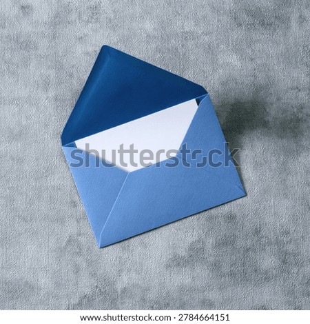A high-angle view of an open blue envelope containing a white sheet of paper, resting on a textured gray surface.