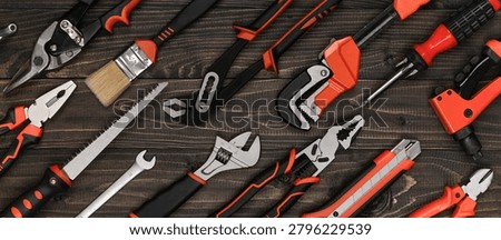 High-angle view of an organized hand tool assortment on a dark wood workshop bench. Professional rustic industrial design layout for hardware store branding and web banners.