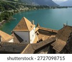 A high-angle view overlooking the orange-tiled rooftops and courtyards of the medieval Chateau de Chillon, situated on the shores of Lake Geneva near Montreux.