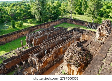 High-angle view of a roofless stone gallery and temple ruins in Angkor Archaeological Park, Cambodia.