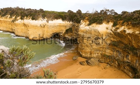 High-angle view of rugged sandstone cliffs and a sandy beach at Loch Ard Gorge.