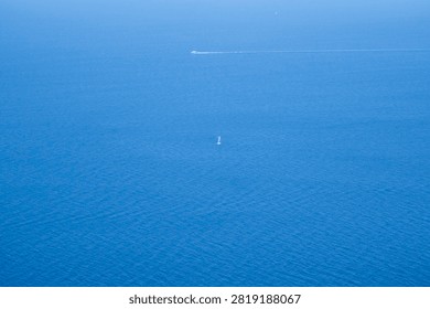 High-angle view of small boats navigating vast deep blue ocean water.