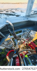 High-angle view from a telecom tower showing safety harness, carabiners and ladder, with snowy farmland and low clouds beyond.