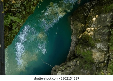 A high-angle view of the turquoise waters of the Soca River flowing through a rocky canyon in Slovenia.