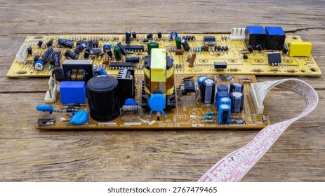A high-angle view of two printed circuit boards with various electronic components like capacitors and resistors on a wooden surface, showcasing intricate hardware engineering and technology.