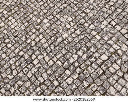 Highangle view of a weathered cobblestone pavement, showcasing a textured diamond pattern.