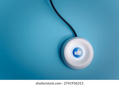 High-angle view of a white button with a blue glowing thumbs up icon on a blue background, representing social media engagement, customer satisfaction, approval, and positive feedback