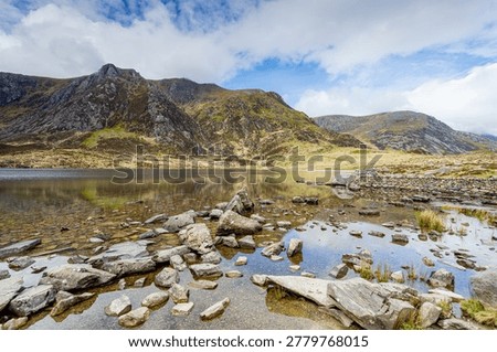 A high-dynamic-range image featuring the ethereal, mist-covered glacial bowl of Cwm Idwal and the still waters of Llyn Idwal. The soft, high-key lighting and atmospheric fog create a serene, dreamlike quality, emphasising the scale and solitude of the Glyderau mountains.