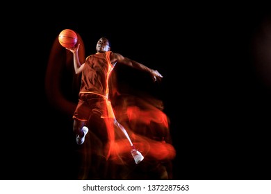 Higher than clouds. African-american young basketball player of red team in action and neon lights over dark studio background. Concept of sport, movement, energy and dynamic, healthy lifestyle. - Powered by Shutterstock