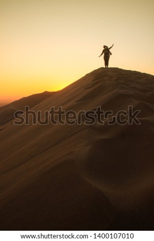 The highest sand dunes in the world at sunset in Namib Desert, in the Namib-Nacluft National Park in Namibia. Sossusvlei. Young woman tourist with backpack stands on top