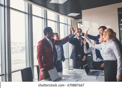 High-five! cheerful young business people giving high-five while their colleagues looking at them and smiling - Powered by Shutterstock