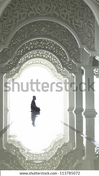 A highkey image of a\
Muslim prays.