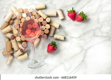 A High-key Overhead Photo Of A Glass Of Rose Wine With Corks And A Fresh Strawberries, On A White Marble Texture With A Place For Text