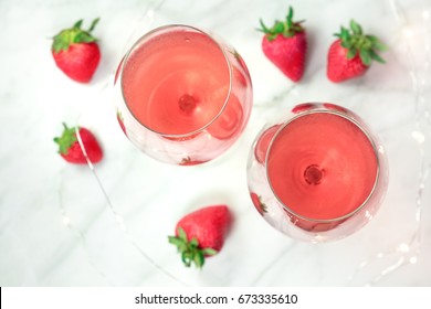 A High-key Overhead Photo Of Two Glasses Of Rose Wine With Strawberries And Fairy Lights, On A White Marble Texture With A Place For Text. Selective Focus