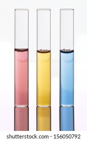 High-key Studio Macro of Three Laboratory Test Tubes Filled with Red, Yellow and Blue Liquids Against a White Background 