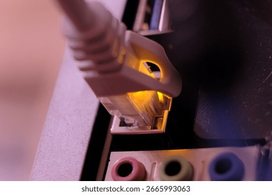 Highlight the precision fit of a network cable connector inserted into a port, with a subtle glow. The blurred background focuses attention on the technical connection, showcasing a professional