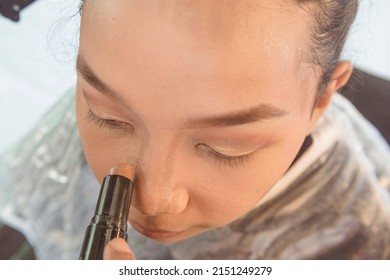 Highlighting the nose of a young asian model with a contour stick. Professional Makeup techniques.