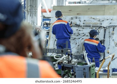 Highlighting precision work. Two technicians meticulously assemble complex wiring harnesses, perfect for electronics, aerospace, manufacturing, and skilled labor themes. Technology and attention to