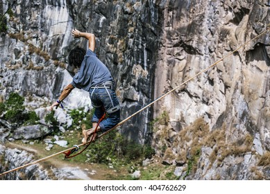 Highliner athlete walking over a rock mountain in a tight rope