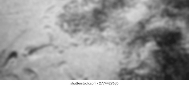 A highly blurred, monochromatic image presenting an abstract texture, possibly suggestive of liquid motion, frosted glass, or ethereal smoke. The lack of sharp focus creates a soft, dreamlike quality with varying shades of gray, inviting interpretation and contemplation.