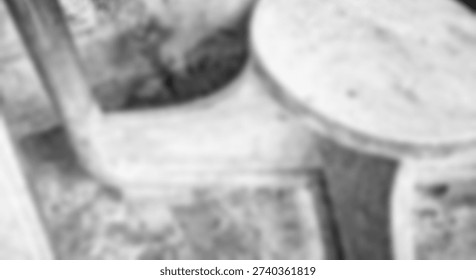 Highly blurred monochrome composition featuring ambiguous shapes suggesting rough textured surfaces or partial structures.