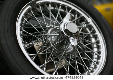 The highly contrasting tyre rubber and polished chrome of a vintage car wheel