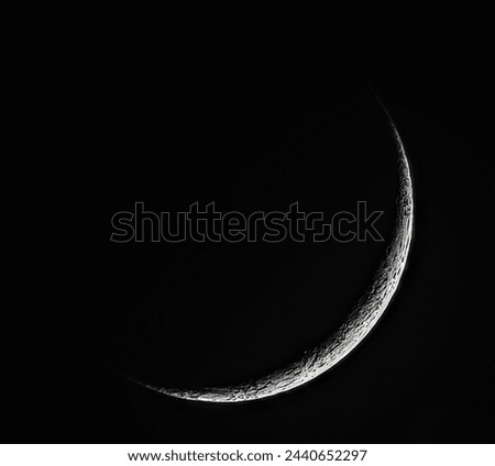 A highly detailed image of a thin crescent moon with clearly visible craters.