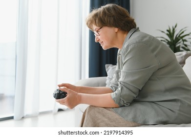 A Highly Emotional Older Lady Sits On The Couch At Home And Plays Video Games. Grandma Wins While Sitting Alone At Home