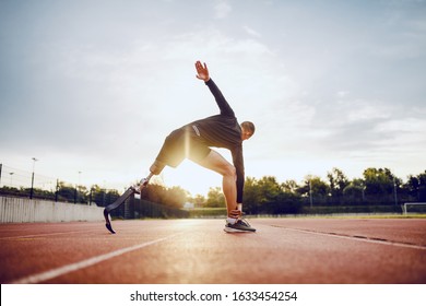 Highly motivated handsome caucasian sporty handicapped man in sportswear and with artificial leg stretching before running while standing on racetrack. - Powered by Shutterstock