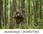 A highly skilled elite sniper, camouflaged in the dense forest, stealthily maneuvers through dangerous woodland terrain on a covert and precise mission