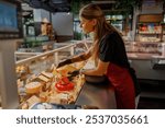 A highly skilled vendor is thoughtfully serving an impressive variety of gourmet cheeses in a lively deli setting