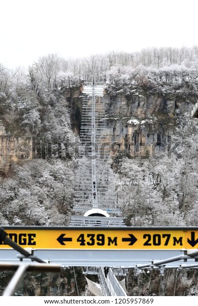 High-mountain, suspended rope bridge,\
which offers stunning views of the gorge, which runs a mountain\
river and a view of the village located far away in the\
valley