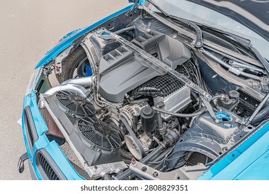 High-performance car engine bay, featuring organized and clean components, including black textured cover, inline-four or inline-six engine, alternator, air intake system, supercharger, air filt.