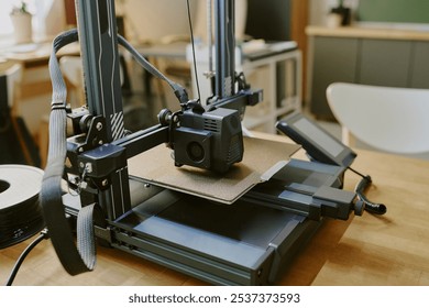 High-precision 3D printer operating in a modern, well-lit workspace, showcasing advanced technology and design. Background includes various devices and an organized setup