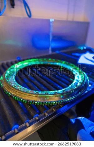 A high-precision aerospace component is undergoing fluorescent penetrant testing with distinctive green indications. Non-destructive evaluation exposes  discontinuities in this critical flight safety 