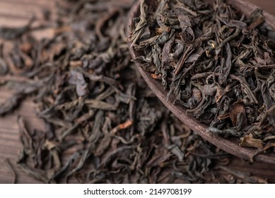 High-quality black tea in wooden spoon and on the table. Dried tea leaves