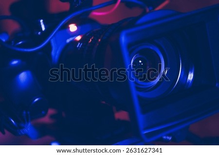 A high-quality camera is positioned in a studio, illuminated by striking purple and red lighting. Cables and equipment surround it, setting the tone for inspiring film projects.