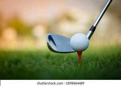 High-quality Golf Club Hitting A White Golf Ball Placed On A Red Peg With Green Grass.